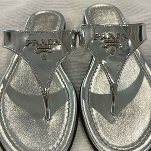Prada Italian size 39. Shiny silver flip-flops with black rubber bottom.